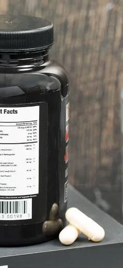 Testosil bottle on a grey bench, turned to show the printed label with its ingredient table, two white capsules beside it